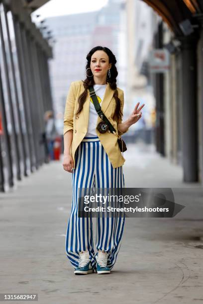 German singer Jasmin Wagner wearing a white shirt with a yellow smiley face by Kule, a yellow blazer by Veronica Beard, blue and white striped pants...