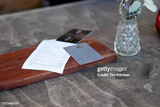 close-up of credit cards and bill on table in rustic restaurant - restaurant bill stock-fotos und bilder