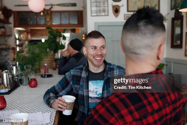 mid-adult male couple smiling at bar counter in restaurant - new york cafe stock-fotos und bilder