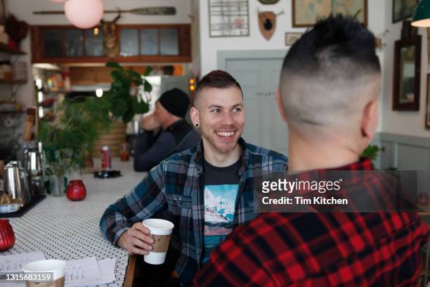 mid-adult male couple smiling at bar counter in restaurant - localidad pequeña fotografías e imágenes de stock