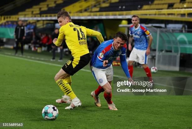 Fabian Reese of Holstein Kiel battles for possession with Lukasz Piszczek of Borussia Dortmund during the DFB Cup semi final match between Borussia...