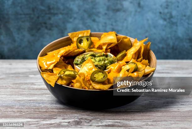 plate of mexican nachos with cheese in a bowl, on wood and dark background. copy space - nachos stock-fotos und bilder