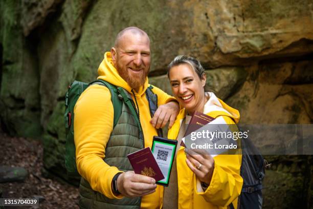 zwei wanderer zeigen ihre digitalen impfpässe - impfpass reisedokument stock-fotos und bilder