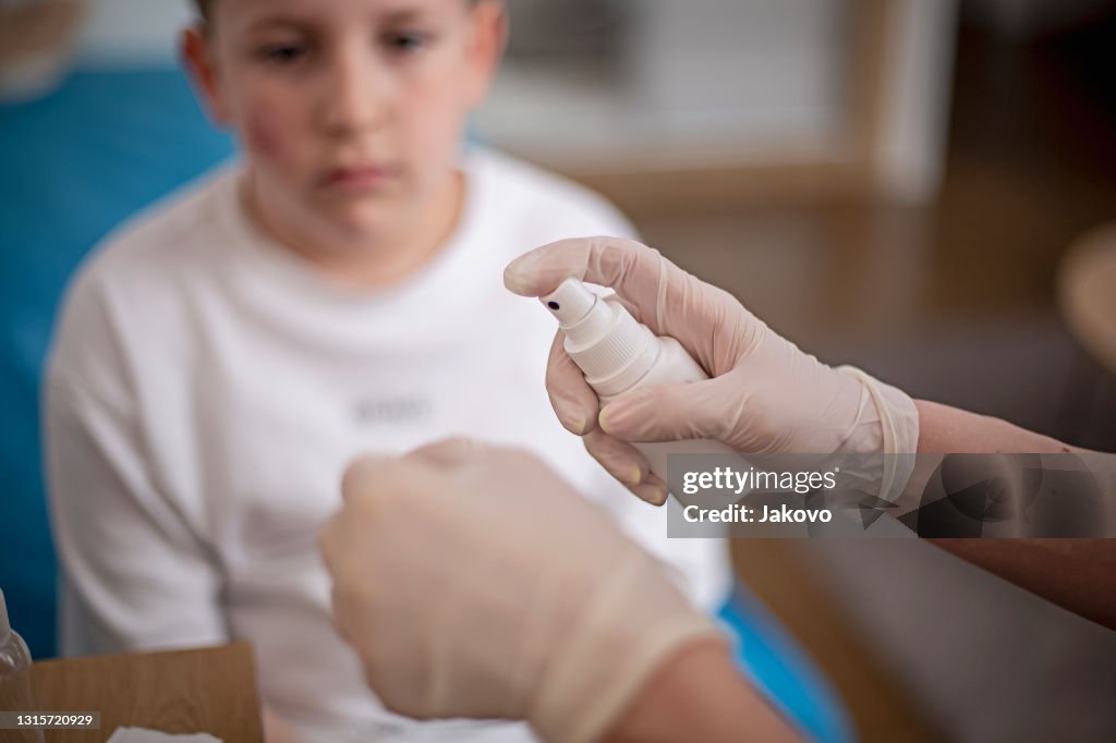 Mother cleaning her son's wound on his cheek