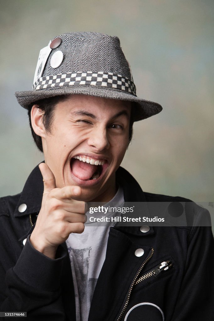 Winking mixed race man making gun gesture with his hand