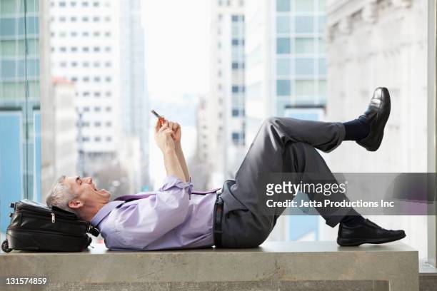caucasian businessman laying on bench text messaging - feet on table stock pictures, royalty-free photos & images