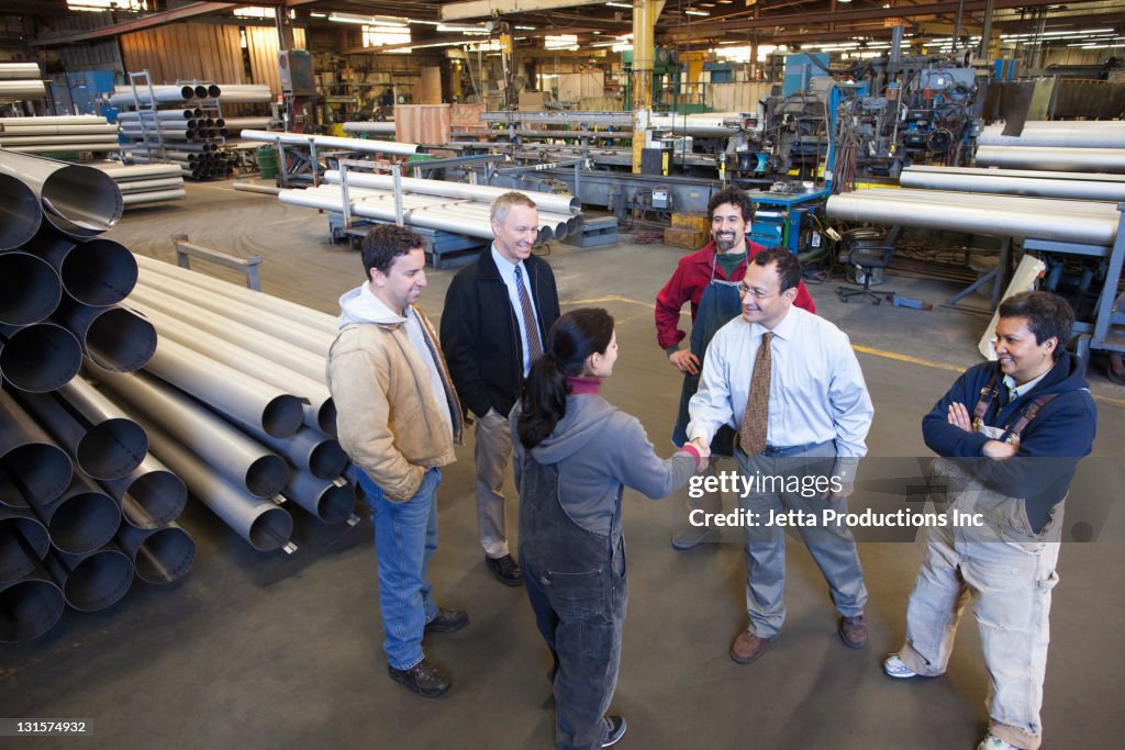 Foreman shaking hands with worker in factory