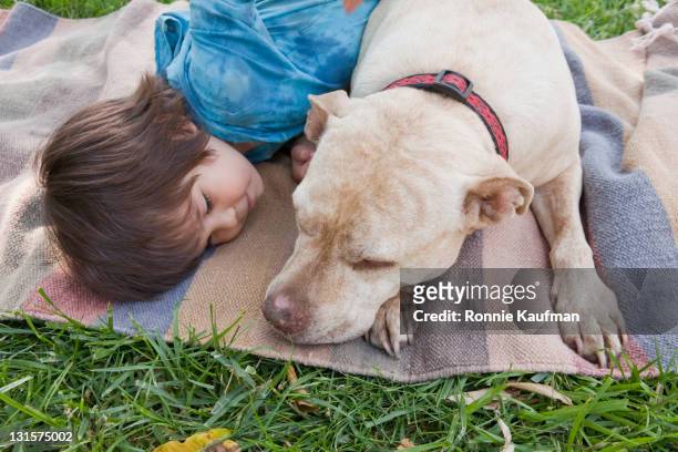 Mixed race boy laying on blanket with dog