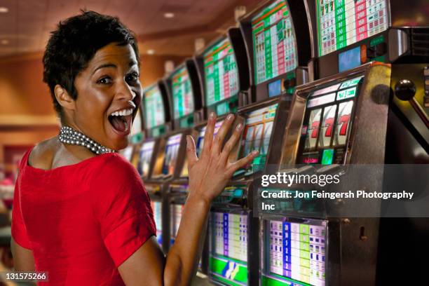 aufgeregt gemischtes frau spielen spielautomaten im casino - casino win stock-fotos und bilder