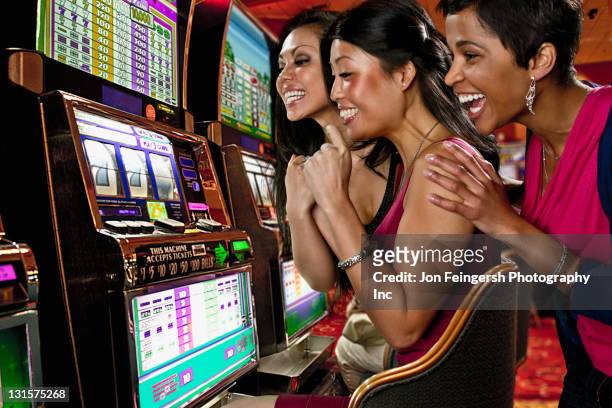 excited women playing slot machines in casino - casino stock pictures, royalty-free photos & images