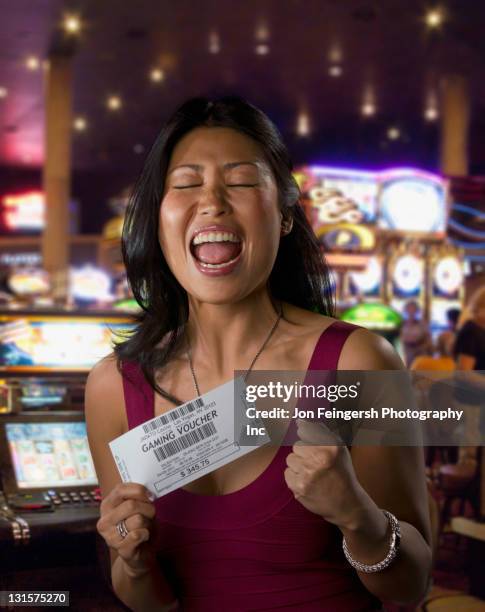 excited chinese woman holding gaming voucher in casino - casino winner stock pictures, royalty-free photos & images