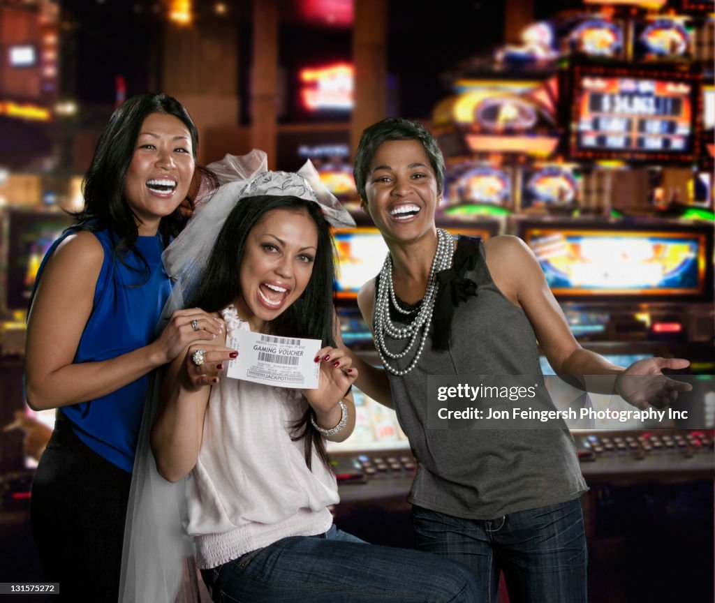 Excited women holding gaming voucher in casino