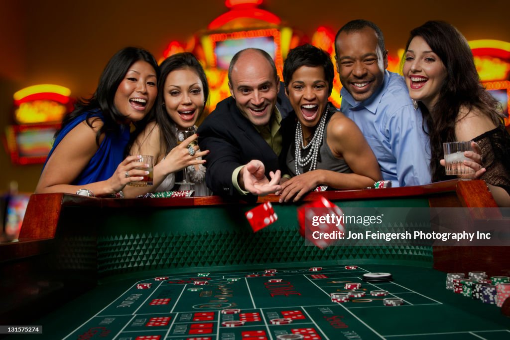 Excited friends gambling at craps table in casino