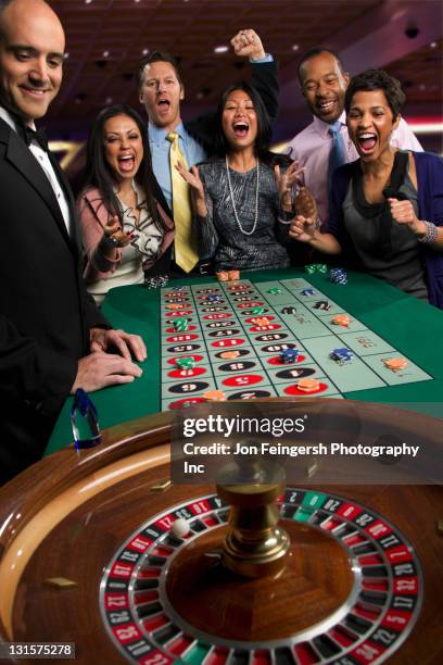 excited friends gambling at roulette table in casino - roulette dealer stock pictures, royalty-free photos & images