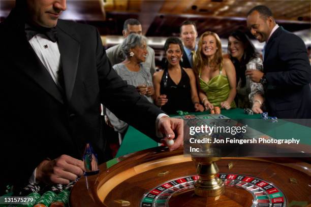 excited friends gambling at roulette table in casino - casino dealer stockfoto's en -beelden