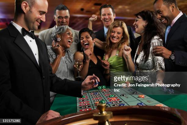 excited friends gambling at roulette table in casino - casino dealer stockfoto's en -beelden