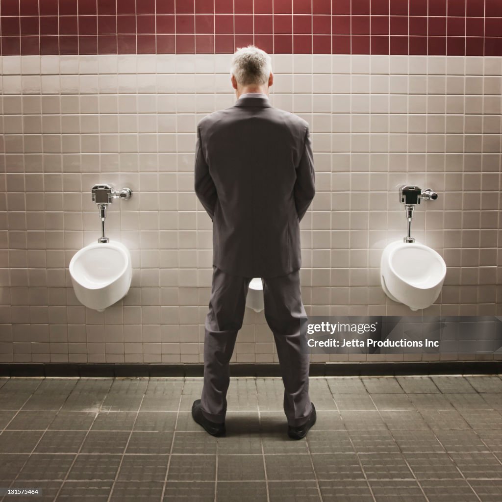 Caucasian businessman using public restroom
