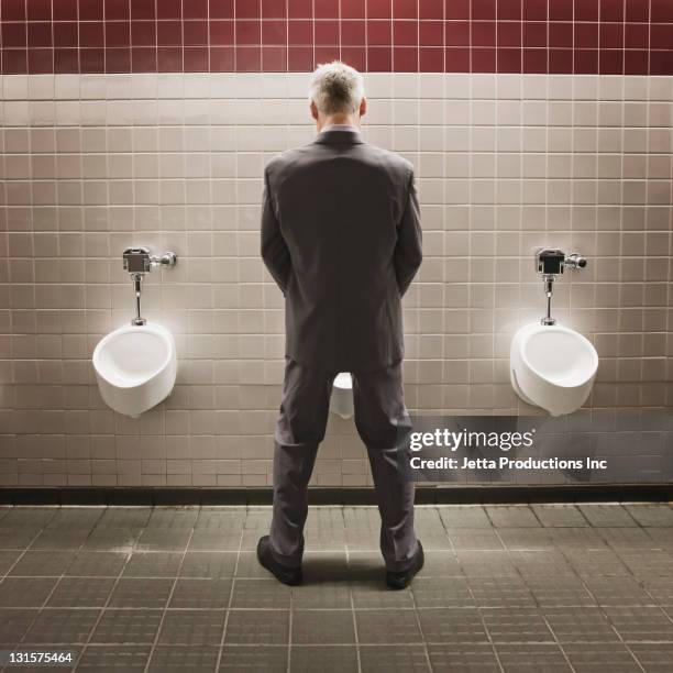 caucasian businessman using public restroom - urine stock pictures, royalty-free photos & images
