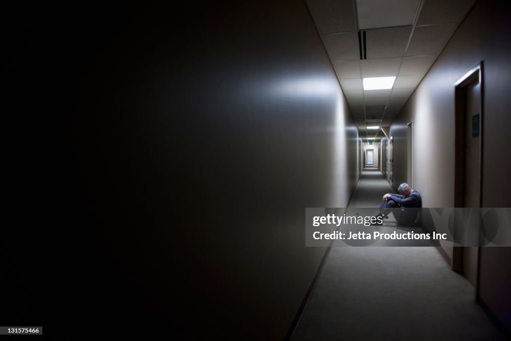 Traurig kaukasischen Geschäftsmann, sitzen auf Boden in Büro-Korridor