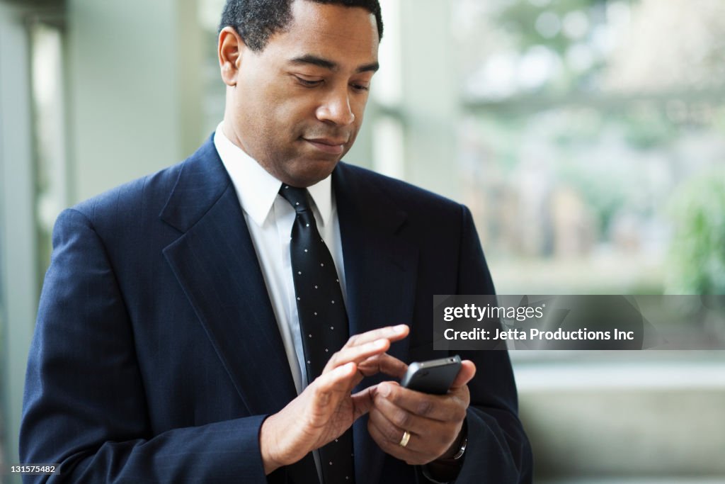 African American businessman text messaging on cell phone