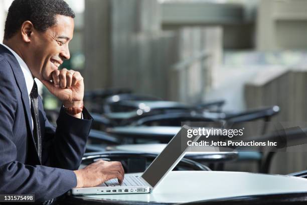 empresario afroamericano usando una computadora portátil en el cafe - mesa cafeteria perfil fotografías e imágenes de stock