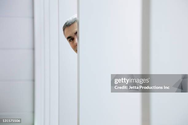 caucasian businessman peering around wall - hiding stock pictures, royalty-free photos & images