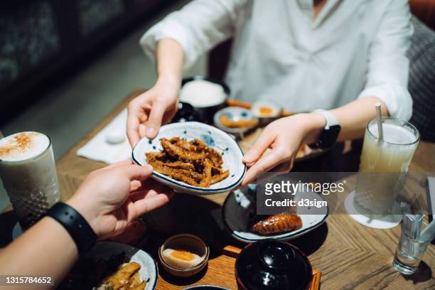 high angle view of young asian woman passing platter of food across table to her boyfriend during meal in a restaurant, enjoying delicate taiwanese cuisine together. asian cuisine and food. eating out lifestyle - seafood platter stockfoto's en -beelden