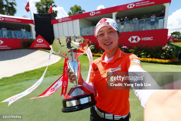 Hyo Joo Kim of South Korea imitates a selfie with the winner's trophy after winning the HSBC Women's World Championship at Sentosa Golf Club on May...