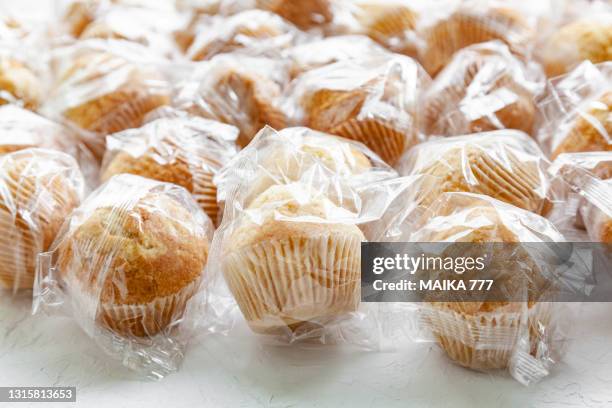 close-up of muffins wrapped individually in cellophane paper. zero waste concept. - polythene stock pictures, royalty-free photos & images