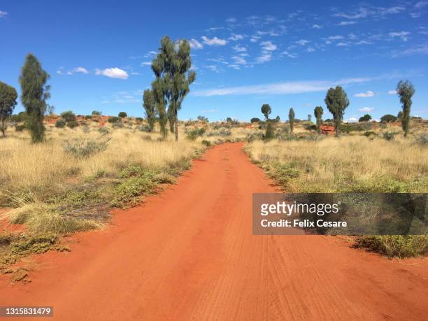 the red dirt roads of the australian outback - ayers rock stock-fotos und bilder