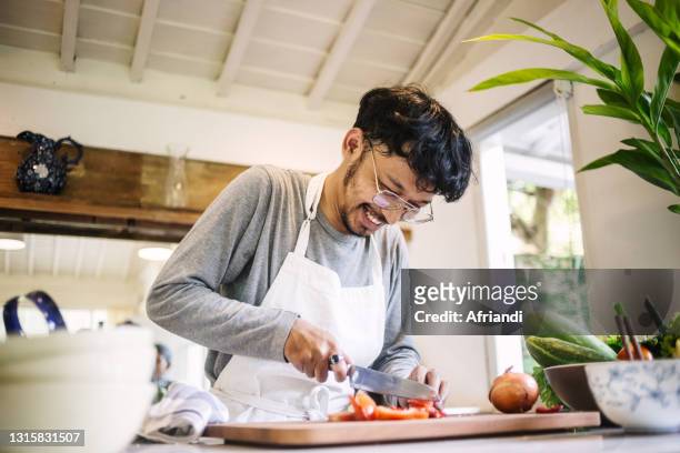 young man preparing to cook - man cooking at home stock pictures, royalty-free photos & images