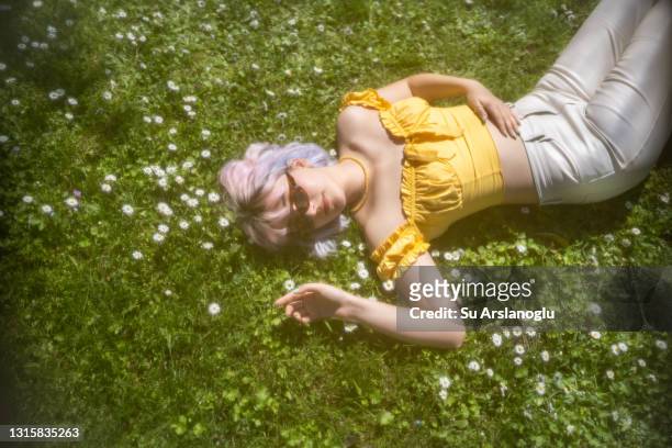 young girl with colored hair lies on the daisy blooming grass - dyed shades imagens e fotografias de stock