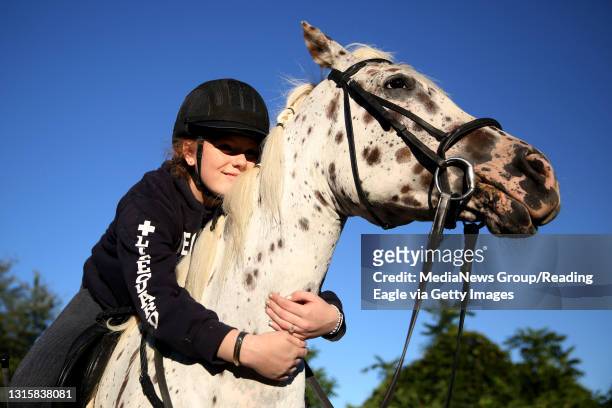 Kara Carman of Ruscombmanor Township, gives her horse, Tinkerbell, a foundation Appaloosa, a hug around the neck during a riding session Monday...