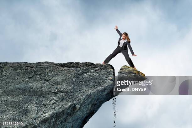 woman balancing on collapsing cliff - capitalism stock pictures, royalty-free photos & images
