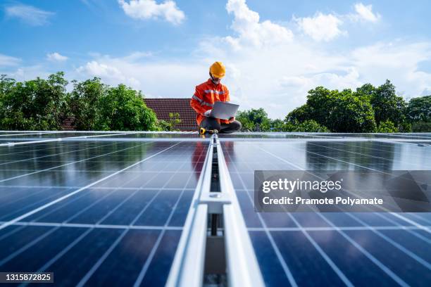 technicians man working with laptop at solar power station on the roof, solar energy technology concept - solar panel installation stock pictures, royalty-free photos & images