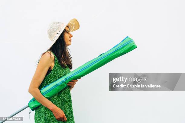 woman prepared to go to the beach with umbrella and straw hat - beach umbrella isolated stockfoto's en -beelden