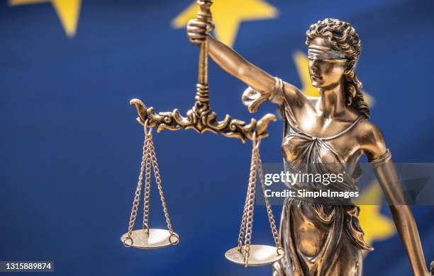 the statue of justice, goddess of justice in front of eu flag. - corrupcion fotografías e imágenes de stock