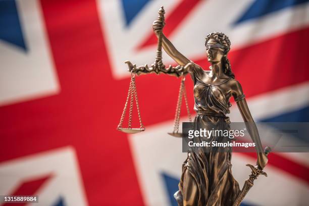 the statue of justice, goddess of justice in front of uk flag. - lady justice stockfoto's en -beelden