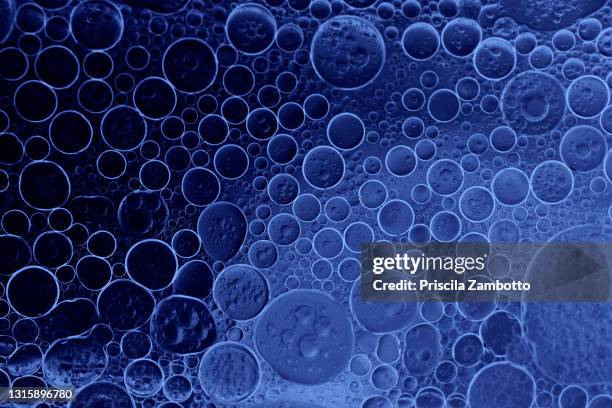 full frame of abstract shapes and textures formed of bubbles and drops oil stains on a blue colored liquid background - food photography dark background blue imagens e fotografias de stock