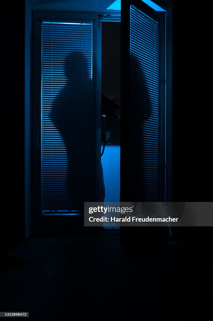 Silhouette eines Einbrechers der gerade in eine Wohnung einbricht