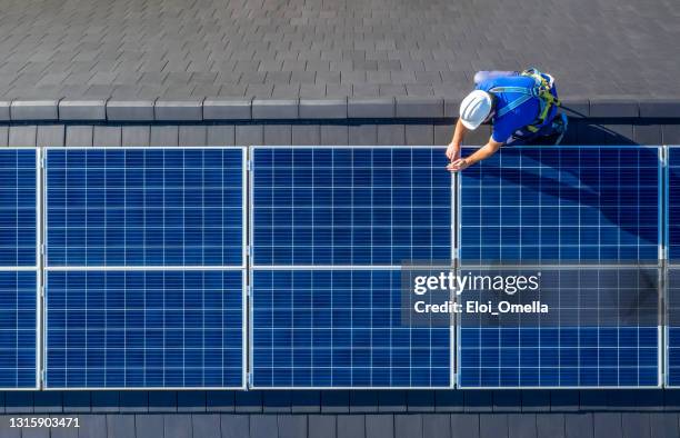 solar panel installer installing solar panels on roof of modern house - installation stock pictures, royalty-free photos & images