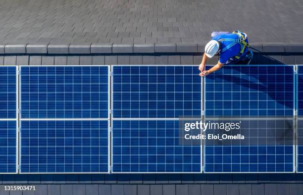 solar panel installer installing solar panels on roof of modern house - painel solar imagens e fotografias de stock