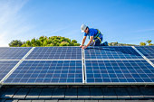 Solar panel installer installing solar panels on roof of modern house