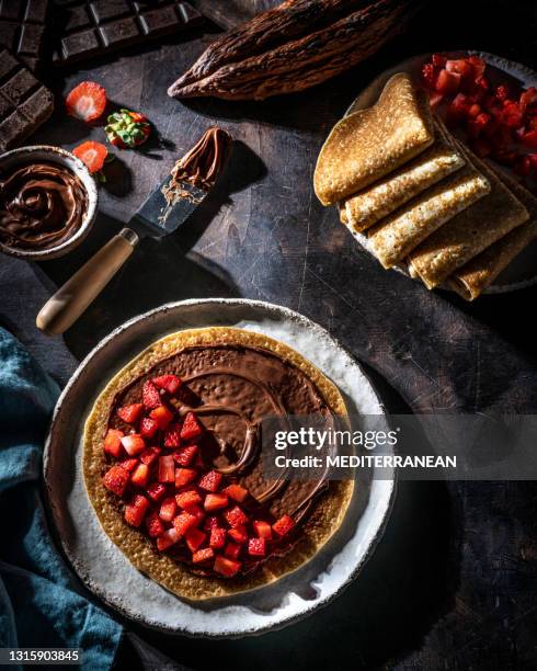 crepes vegan crêpes with cocoa cream chocolate spread and strawberries on dark wood background - nutella pancake stock pictures, royalty-free photos & images