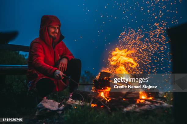 man lights a campfire in the mountains - bonfire stock pictures, royalty-free photos & images