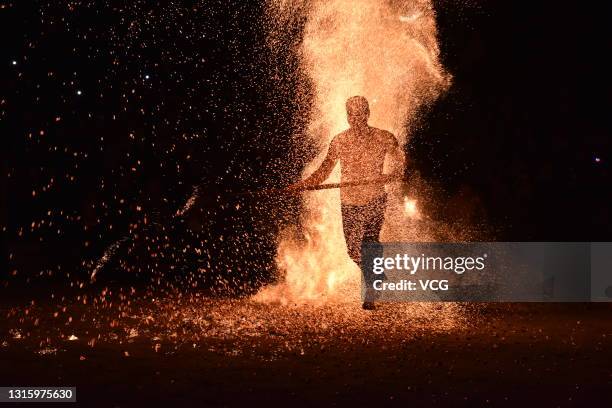 Barefooted man walks through burning charcoal as he performs the traditional ritual called 'Lianhuo', or 'fire walking', on the second day of the May...