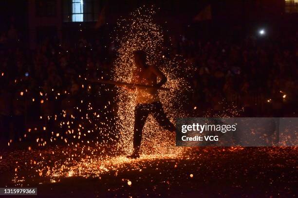 Barefooted man walks through burning charcoal as he performs the traditional ritual called 'Lianhuo', or 'fire walking', on the second day of the May...