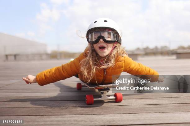 a young girl laying on a skateboard, seeming to fly - playing stockfoto's en -beelden