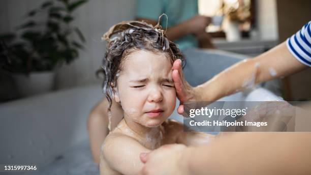 mother with upset small children in bathroom at home, stinging eyes from soap. - kid bath mother stockfoto's en -beelden