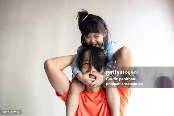 asian kid riding on the nect her dad in home. - nect stock pictures, royalty-free photos & images